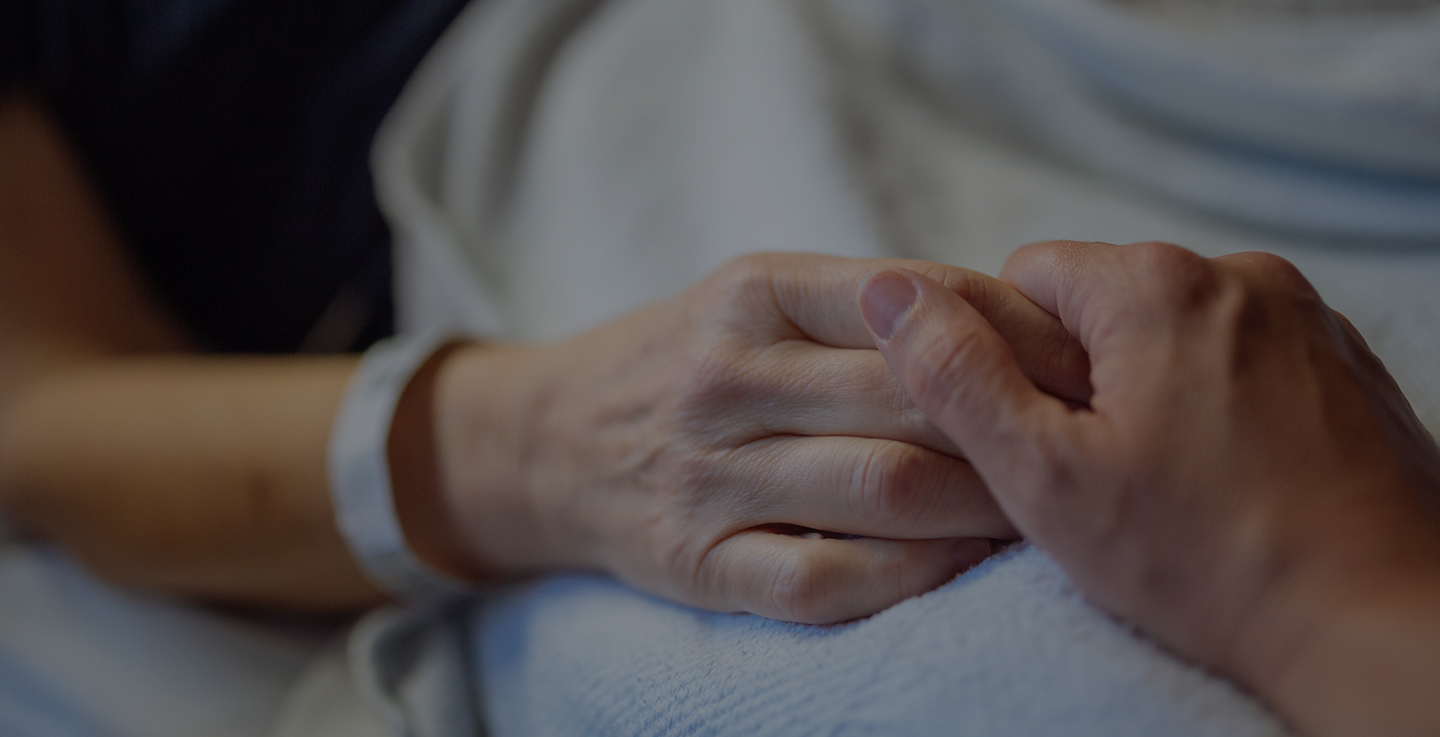 A cancer patient wearing a hospital bracelet holds hands with a loved one at AdventHealth Cancer Institute