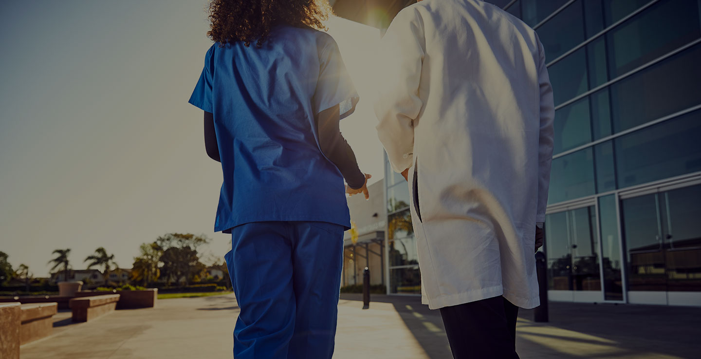 Two physicians at Florida Hospital Cancer Institute walk towards the hospital's front doors