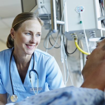 A nurse navigator smiles as she speaks with a patient who lying in bed about Florida Hospital's advanced chemotherapy program