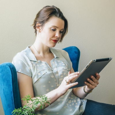 woman in blue chair looking at tablet