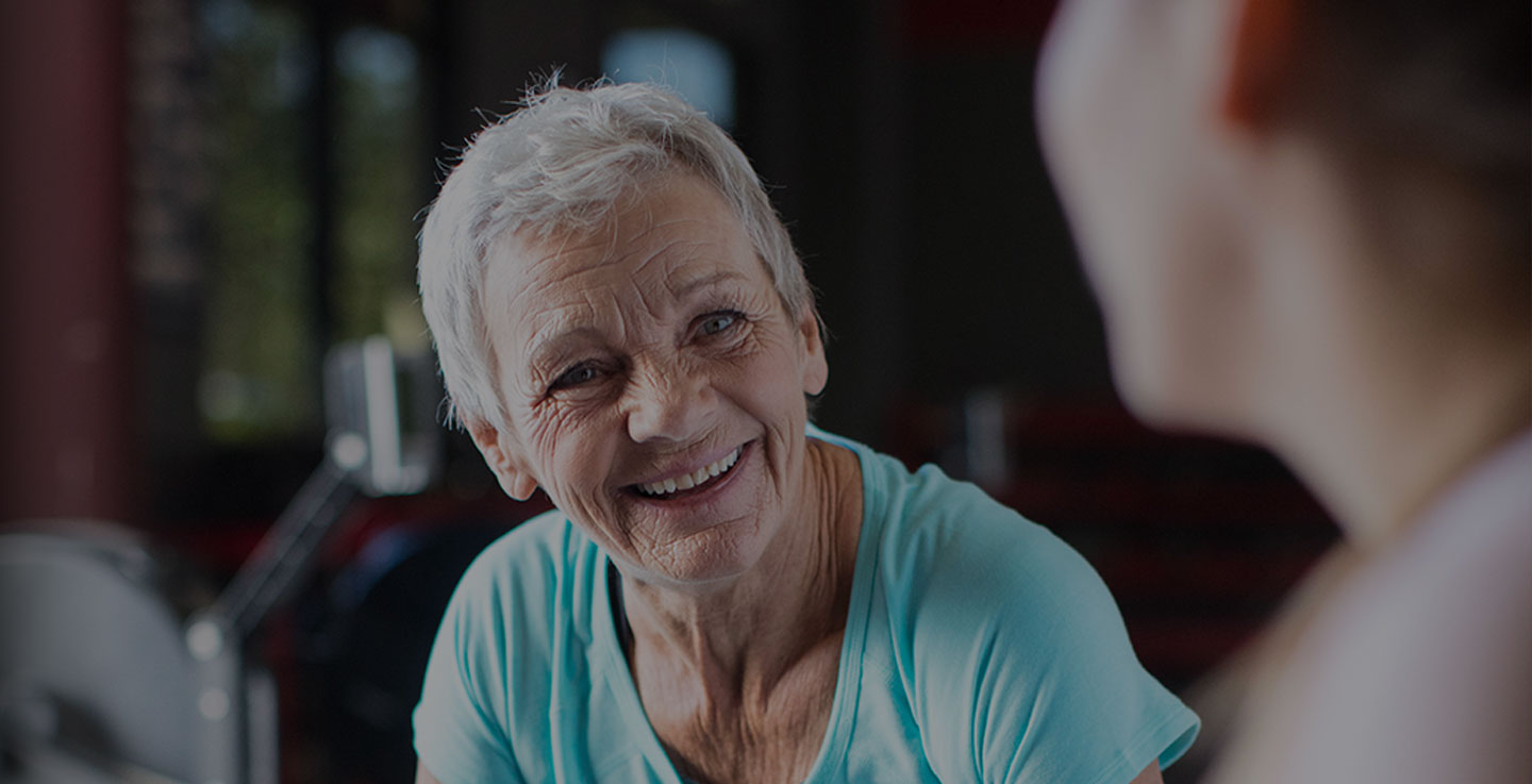 A woman seated in a gym smiles as she enjoys life after cancer treatment