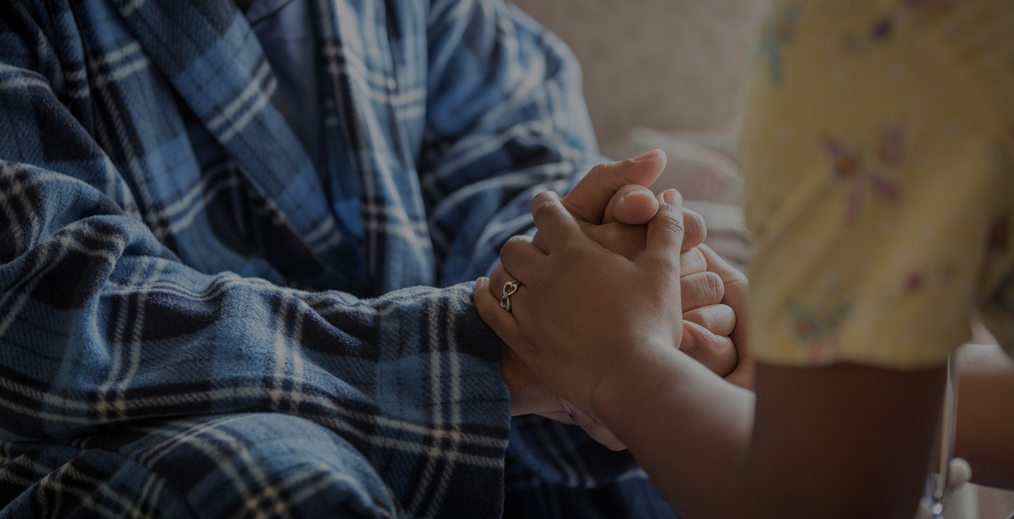 A patient and a cancer care specialist hold hands and discuss AdventHealth's caregiver support options