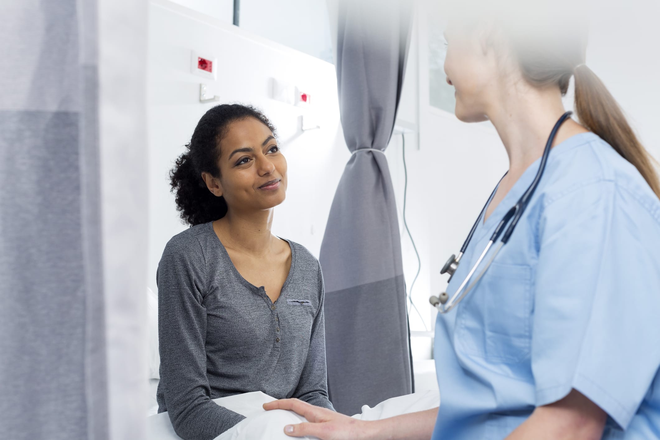 A patient receiving chemotherapy and a cancer treatment specialist look at photos on a phone together 