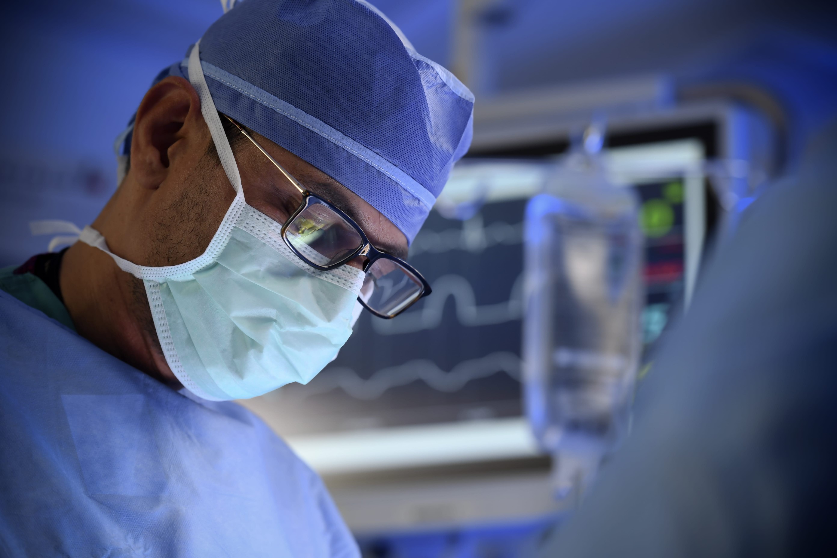 A leading otolaryngologist (ear, nose, and throat surgeon) dressed in surgical attire performs a clinical trial procedure