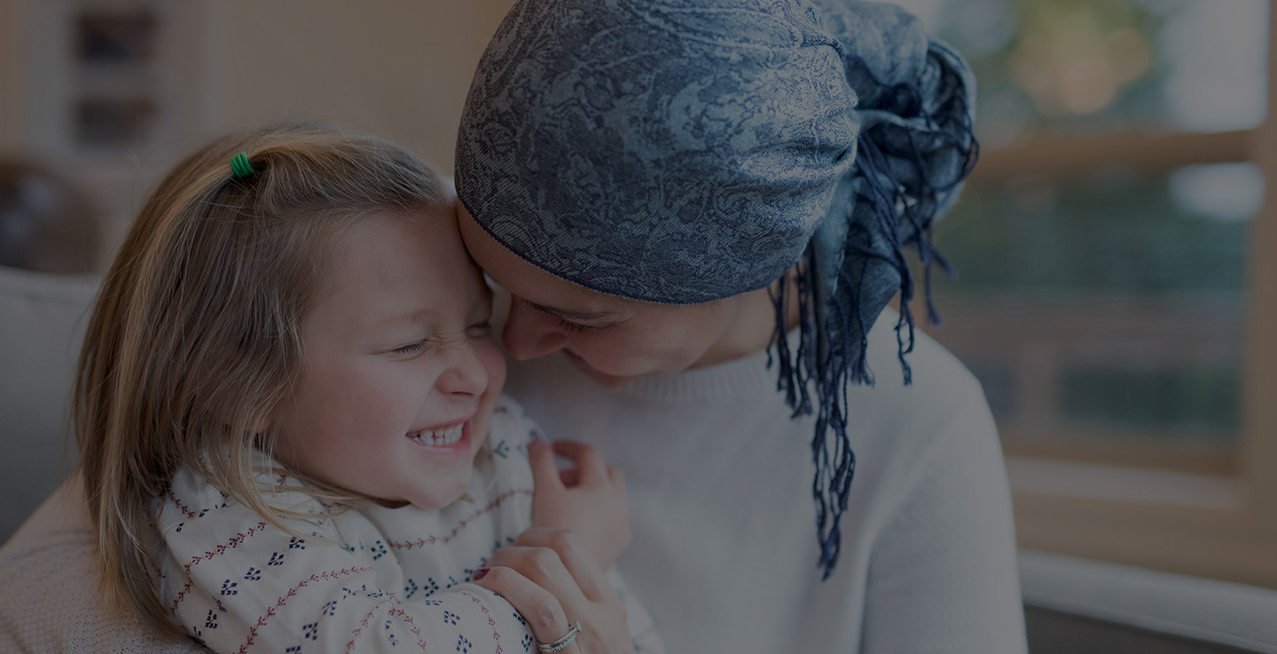 A mother with cancer laughs while holding her daughter