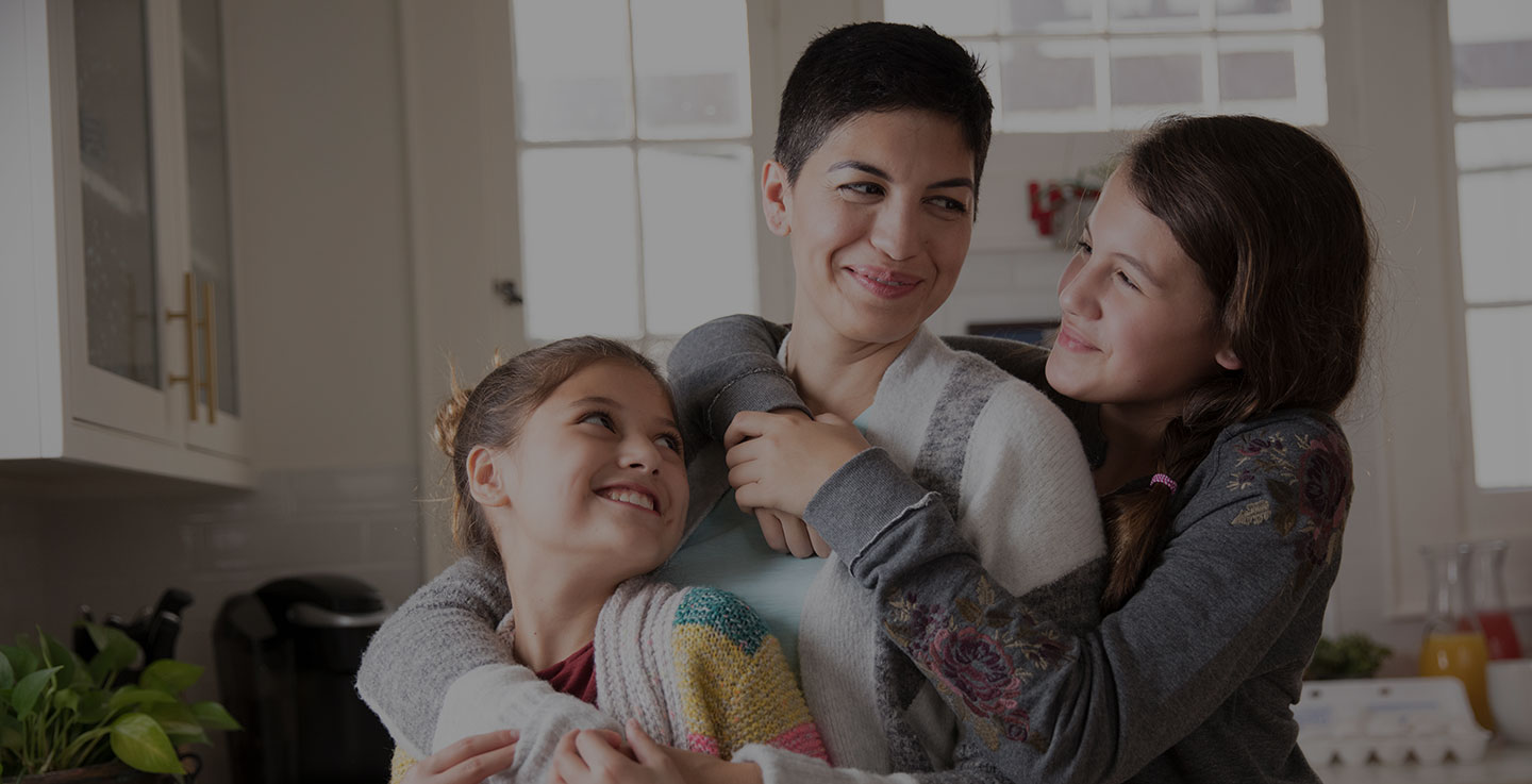 Mother and kids embracing in a kitchen.