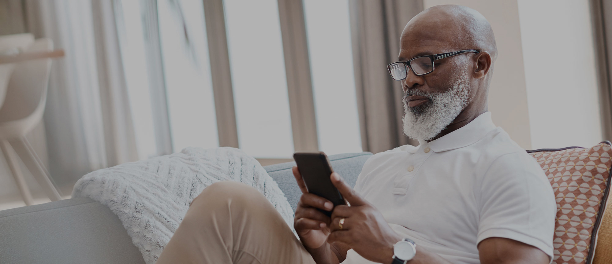 A man checking his phone from the couch. 