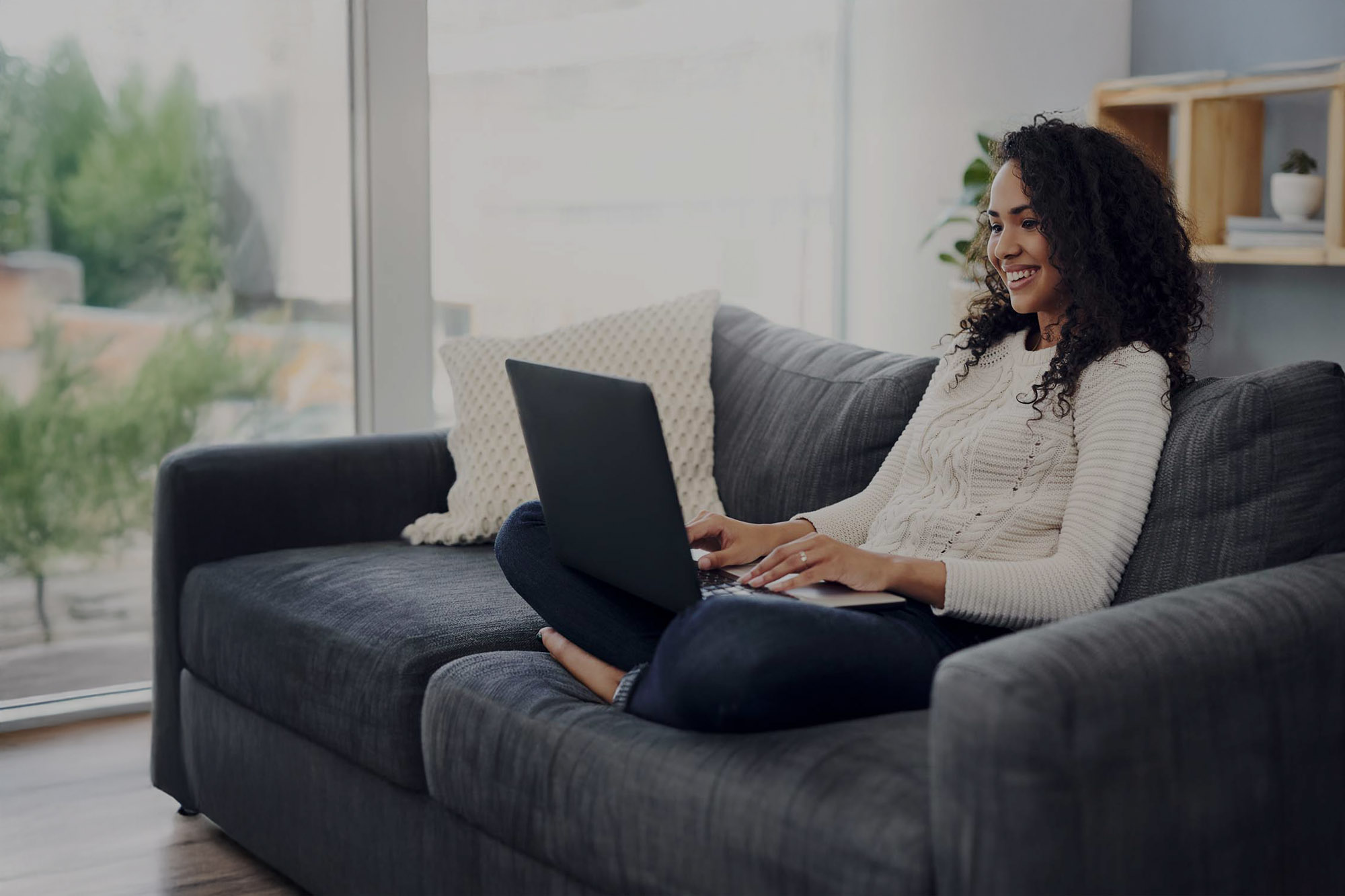 A woman sitting on a couch using a computer.
