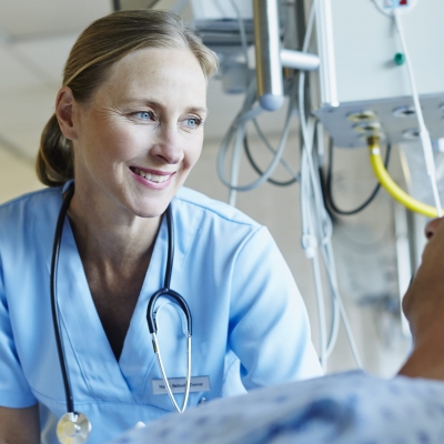 A nurse navigator smiles as she speaks with a patient who lying in bed about Florida Hospital's advanced cancer imaging technology