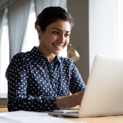 A young woman reading on a laptop.